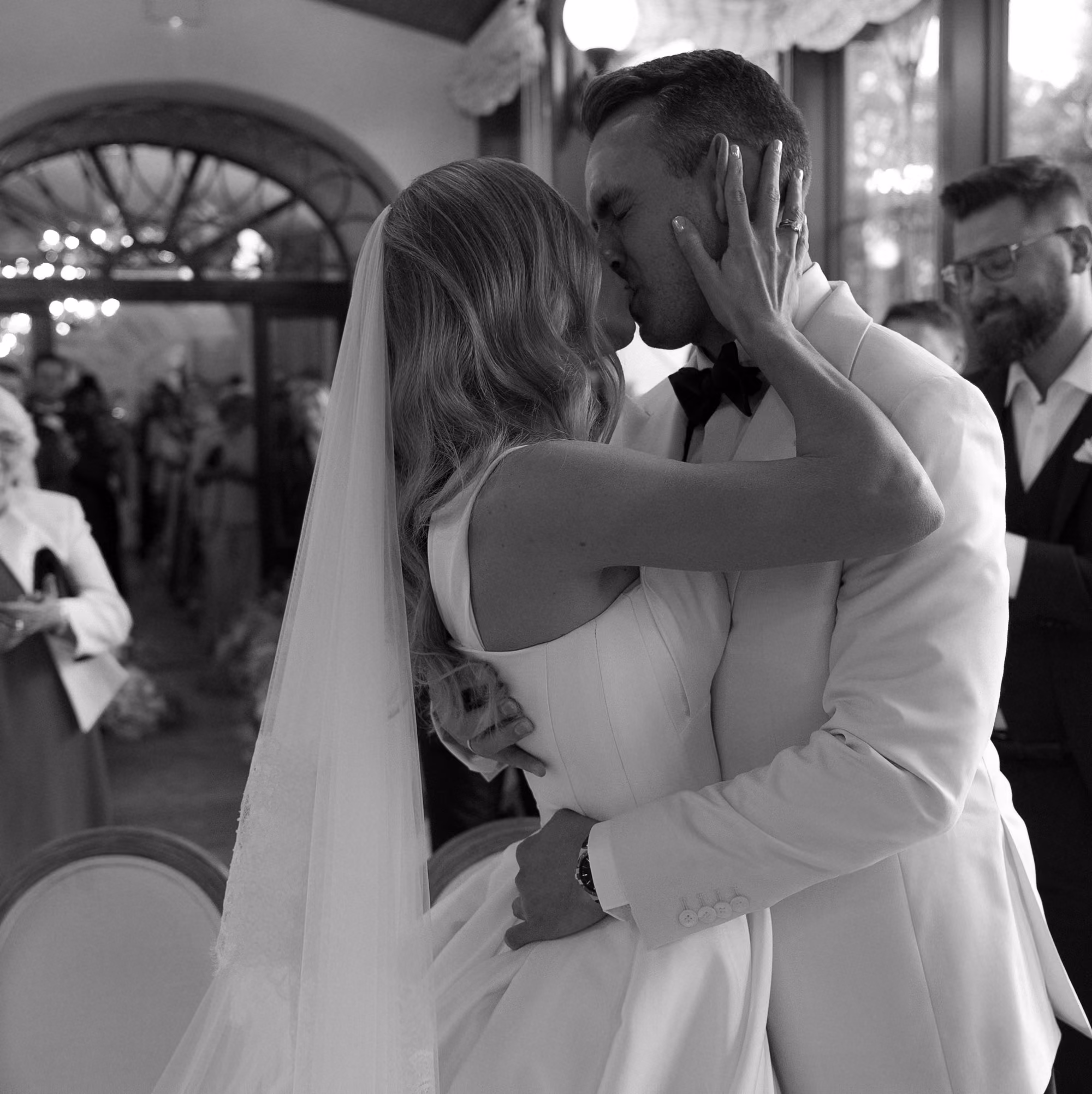 Bride and groom kissing closely at their wedding ceremony in a decorated indoor venue.