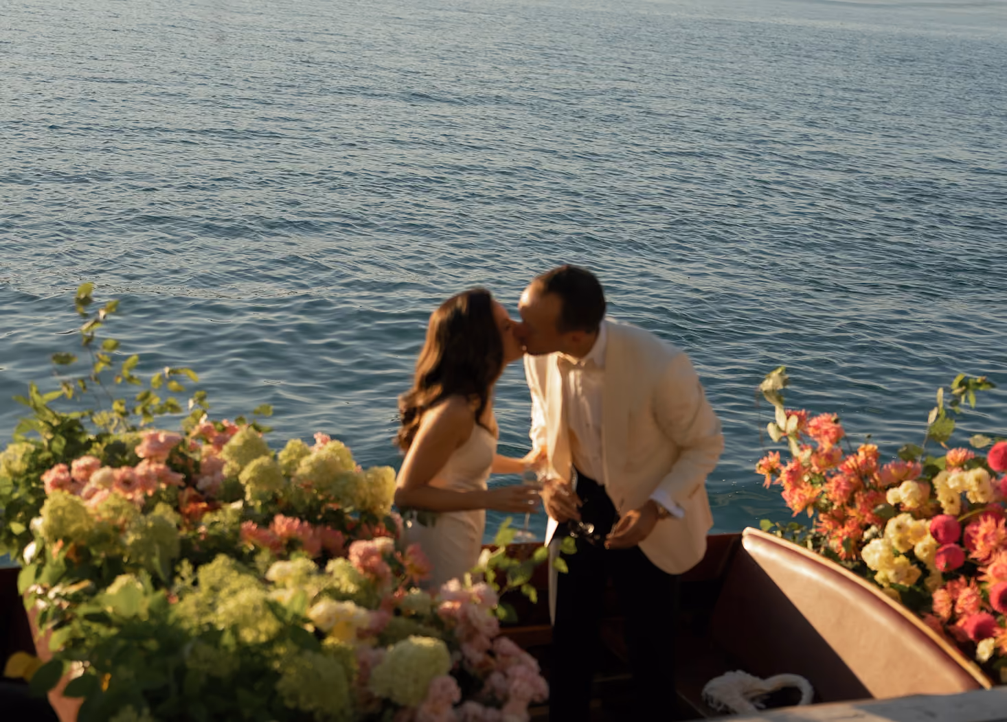 Couple kissing on a flower-decorated boat with water in the background.