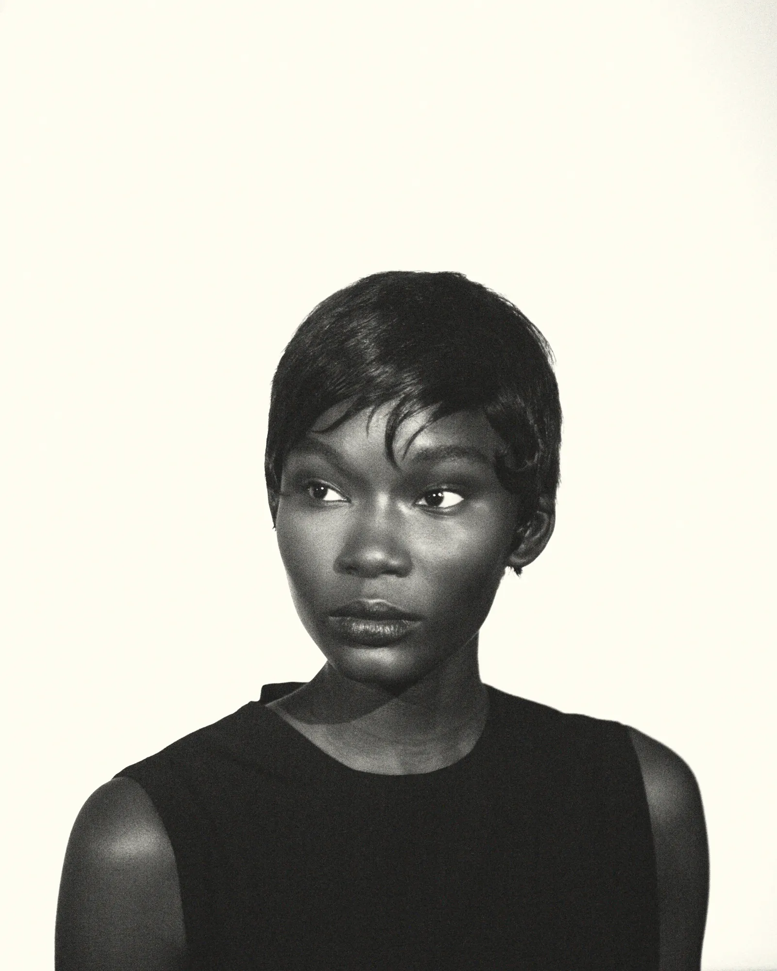 Black and white portrait of a woman with short hair wearing a sleeveless top looking to her left.