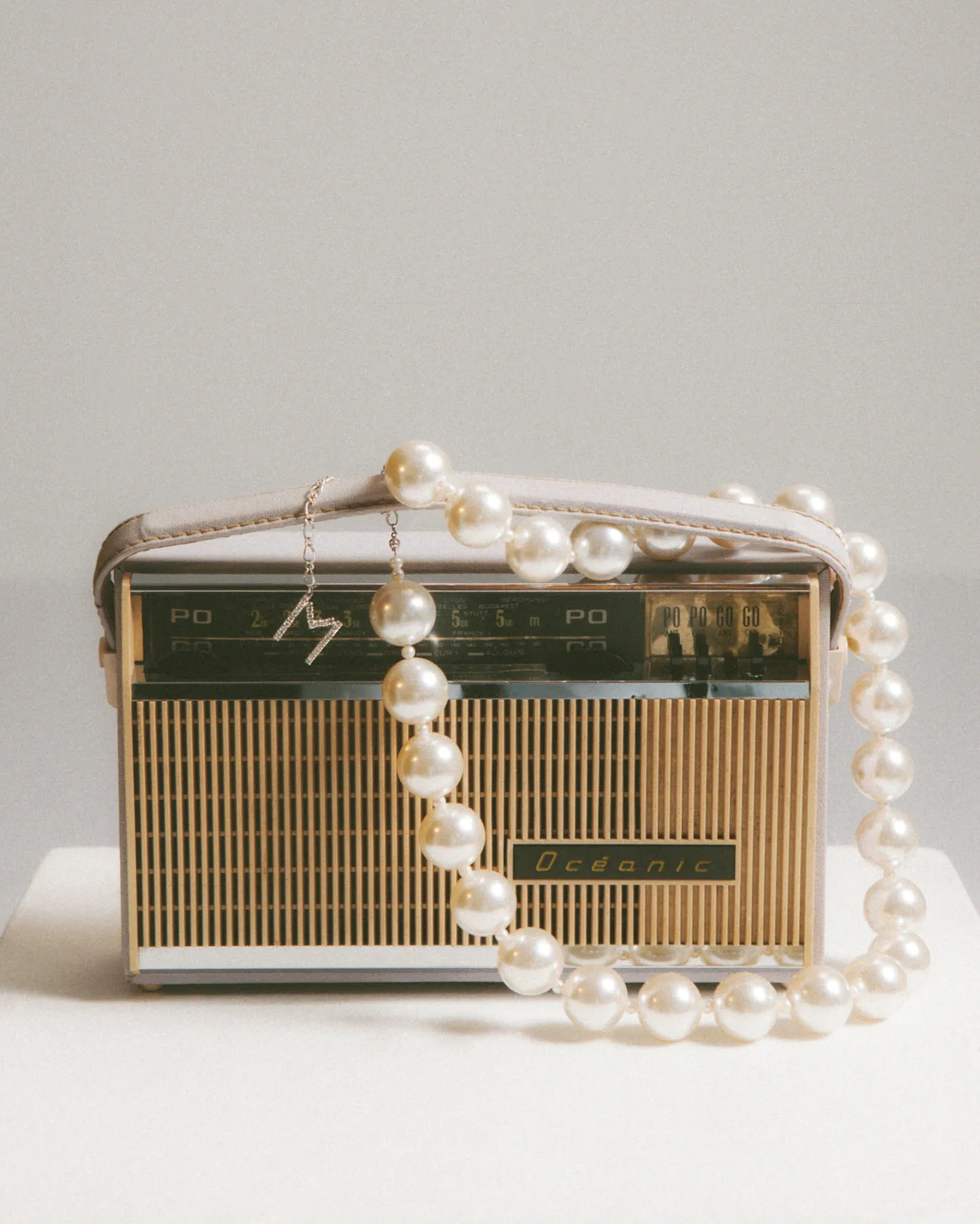 Vintage Océanic radio adorned with a strand of large white pearls draped over it.