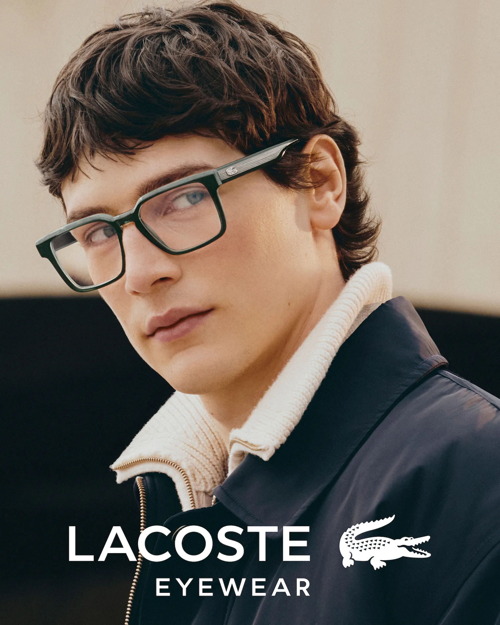 Shirtless young man stands in a field wearing oversized black pants clipped to a wire behind him.