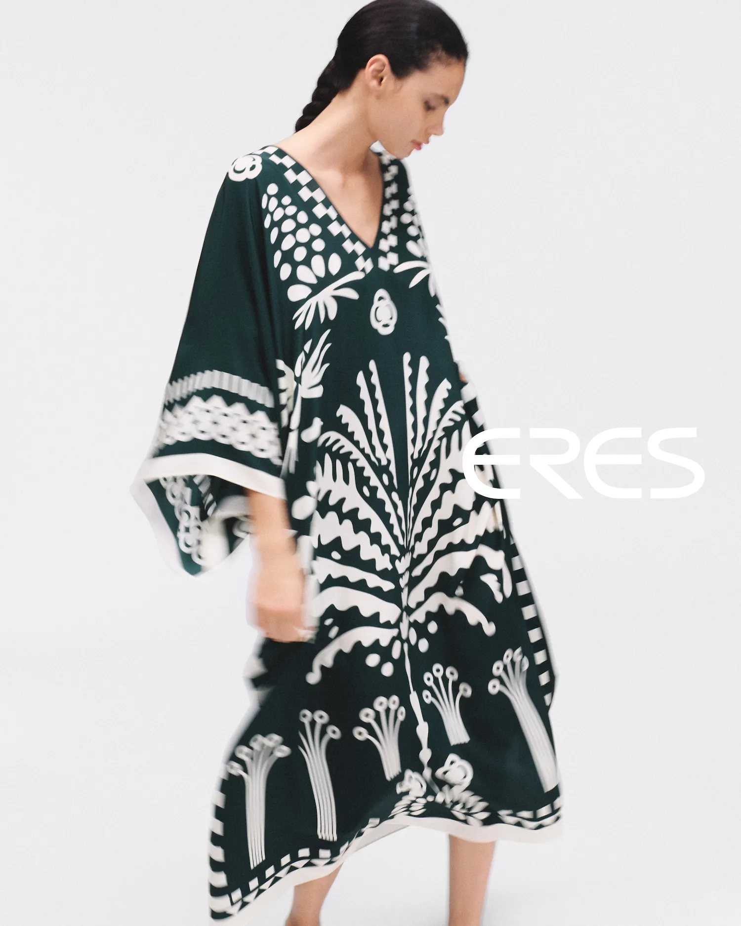 Woman with braided hair wearing a loose black and white dress with bold floral patterns.