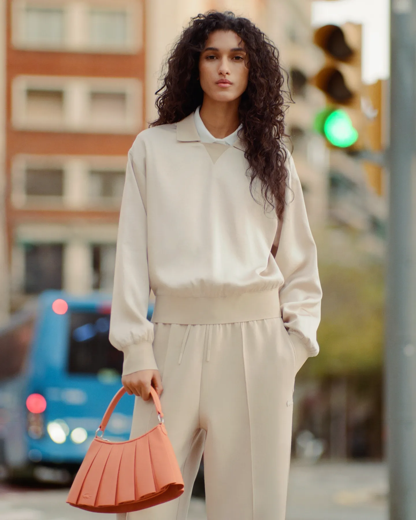 Person wearing taupe suede sneakers with white soles and beige pants sitting on a woven mat indoors.
