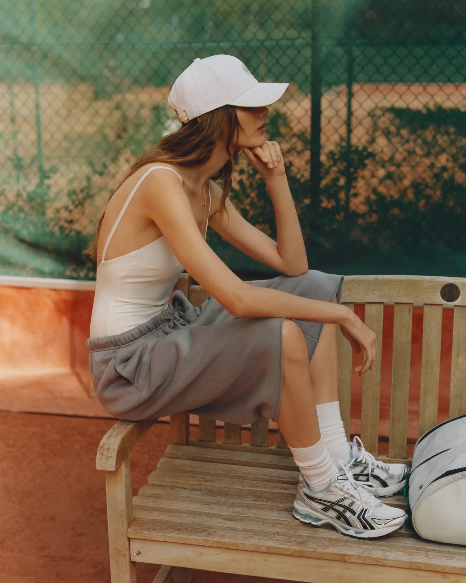 Close-up of beige sneakers with white soles worn with beige pants on tiled floor and woven mat.