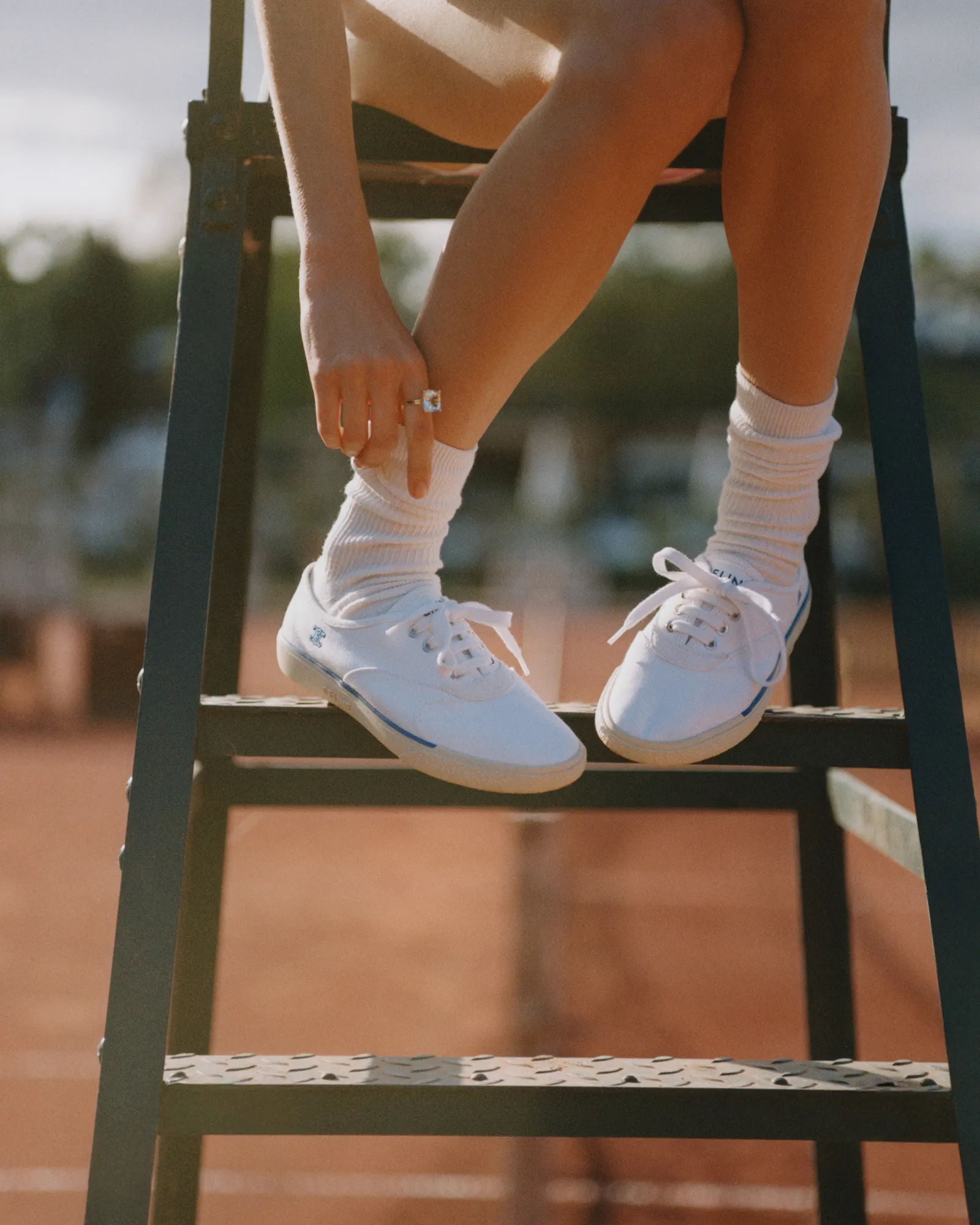 Pair of dark blue suede sneakers with white midsoles resting on a stone surface.