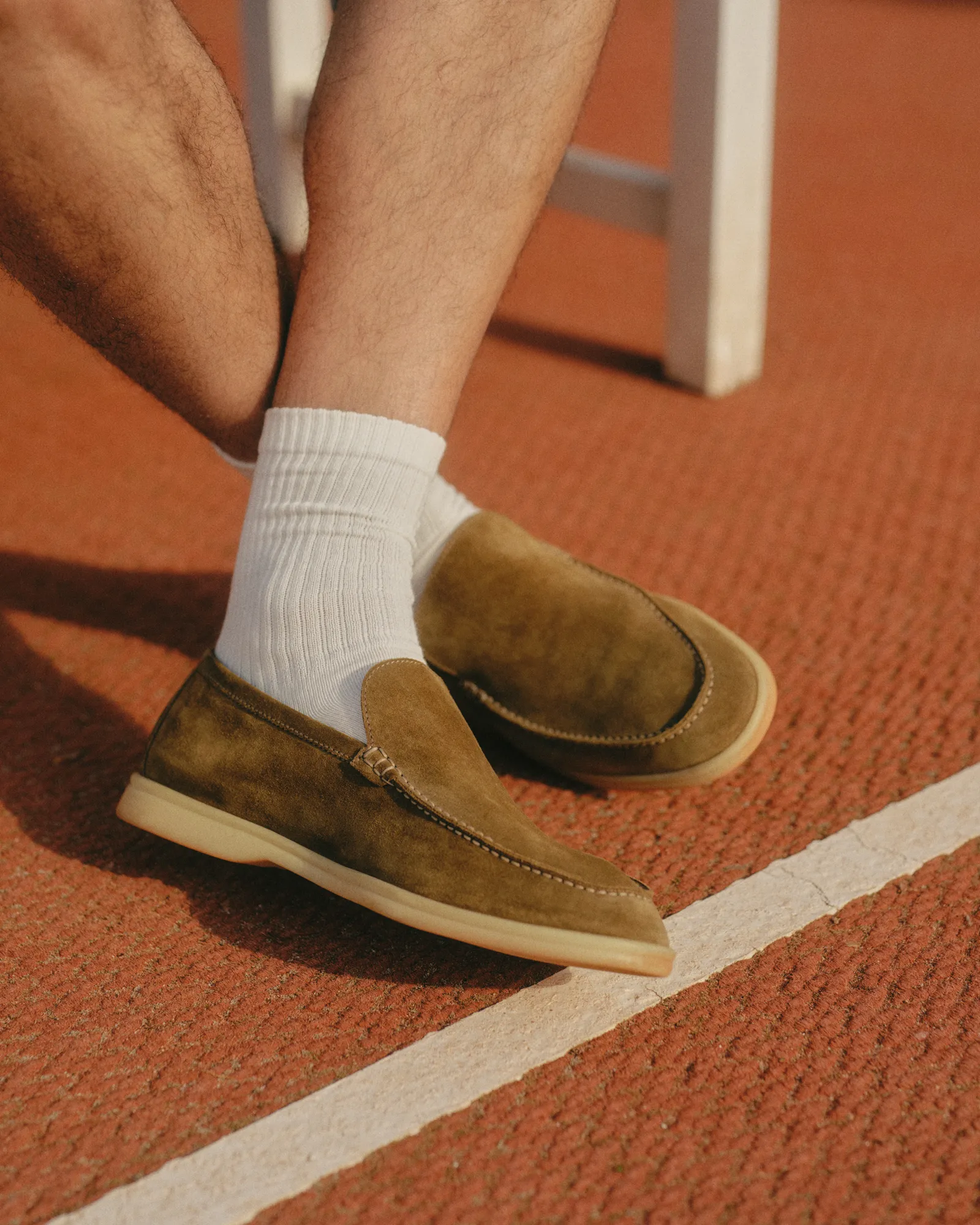 Pair of dark blue suede sneakers with white midsoles resting on a stone surface.