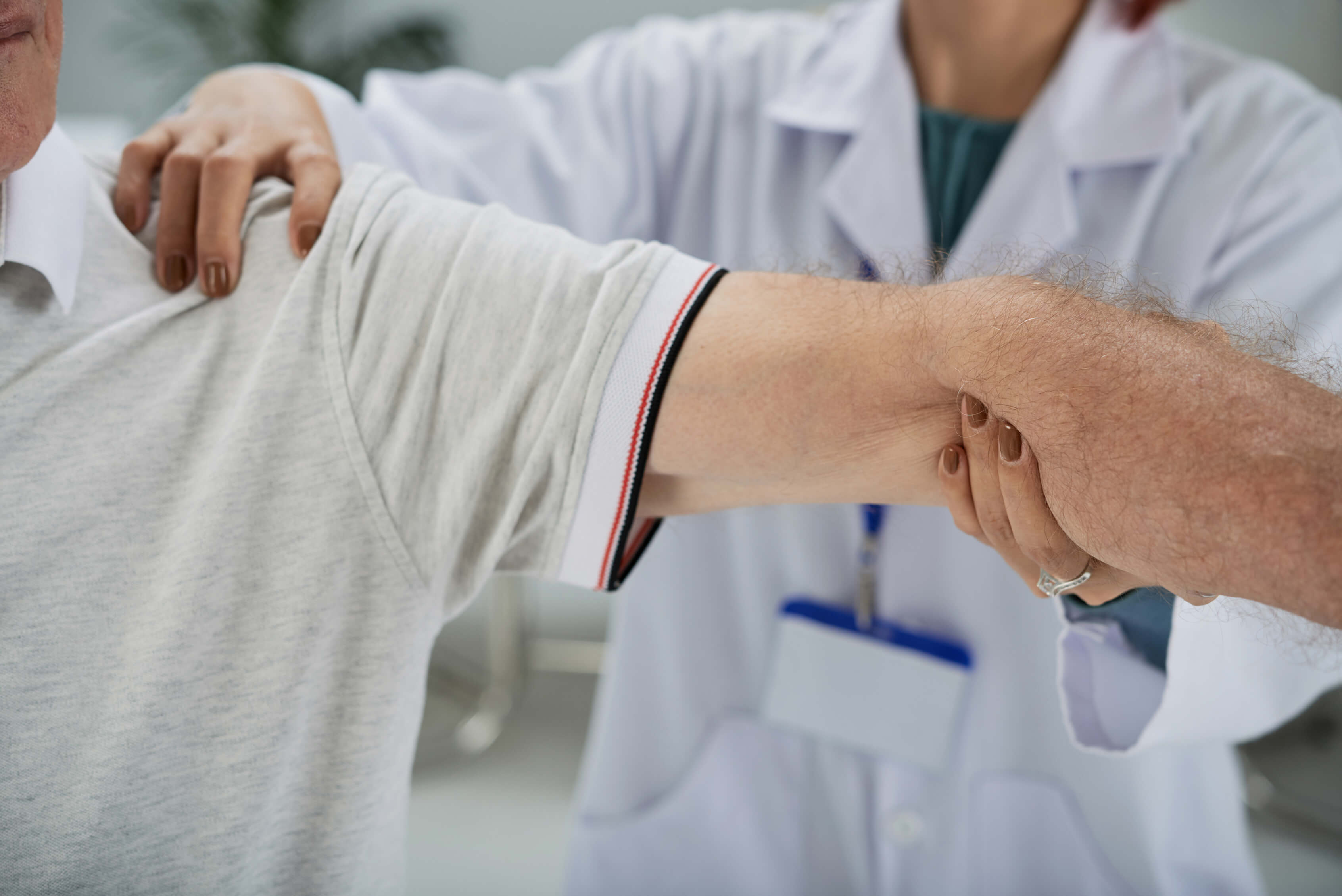 Doctor examining an older man's arm and shoulder during a check-up