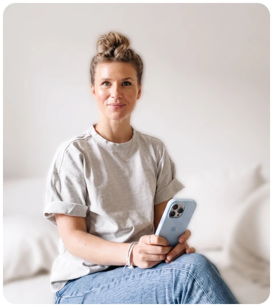 MindClub-Expertin sitzt mit einem Smartphone in der Hand auf einem Sofa
