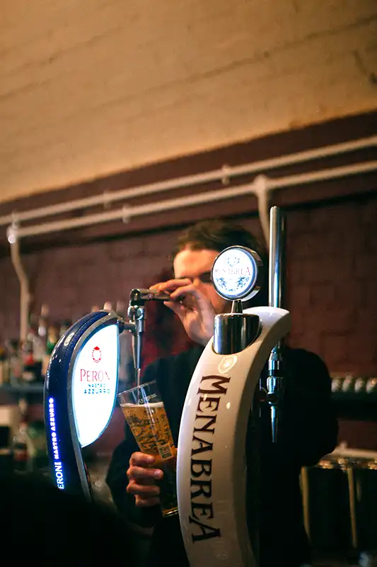 A waiter pouring a Peroni at Chin-Zano restaurant