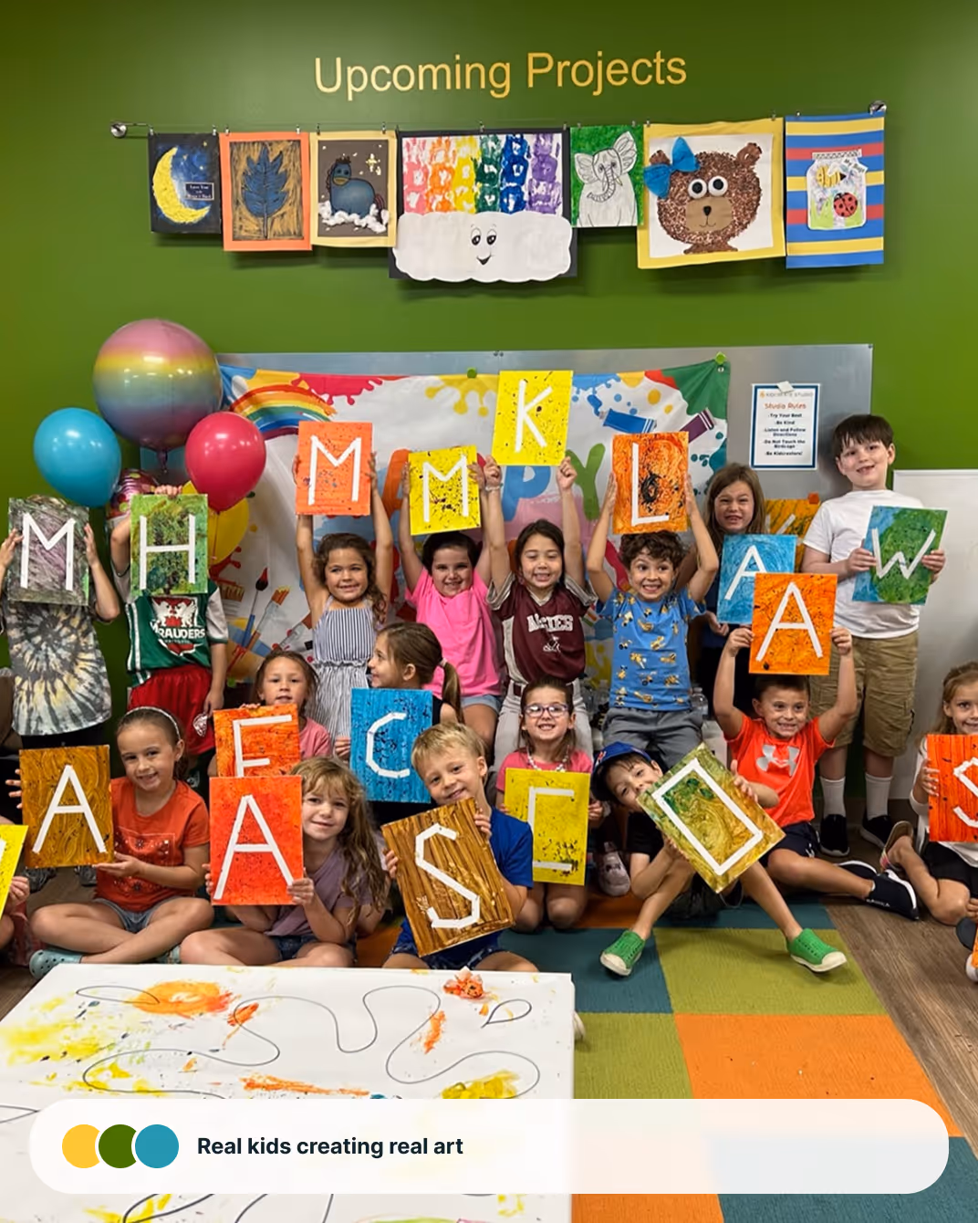 A joyful child celebrating with arms raised in a colorful Kidcreate art studio