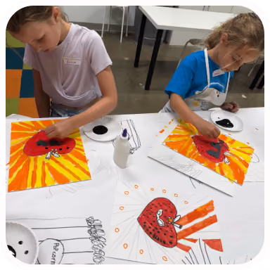 Two kids working on bright heart-themed paintings in class