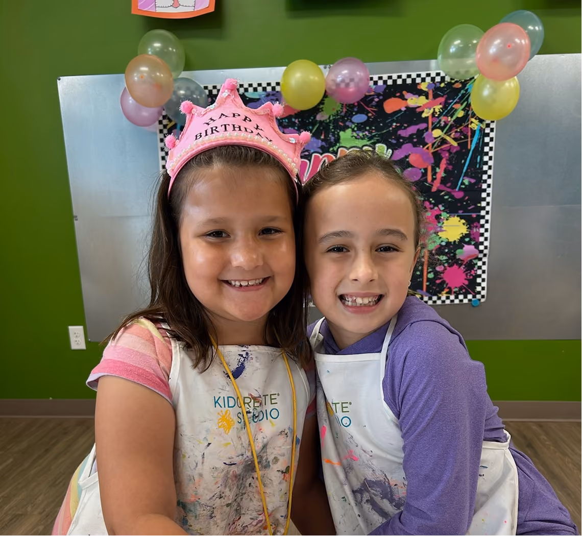 Kids gathered around a long painted birthday party table at Kidcreate