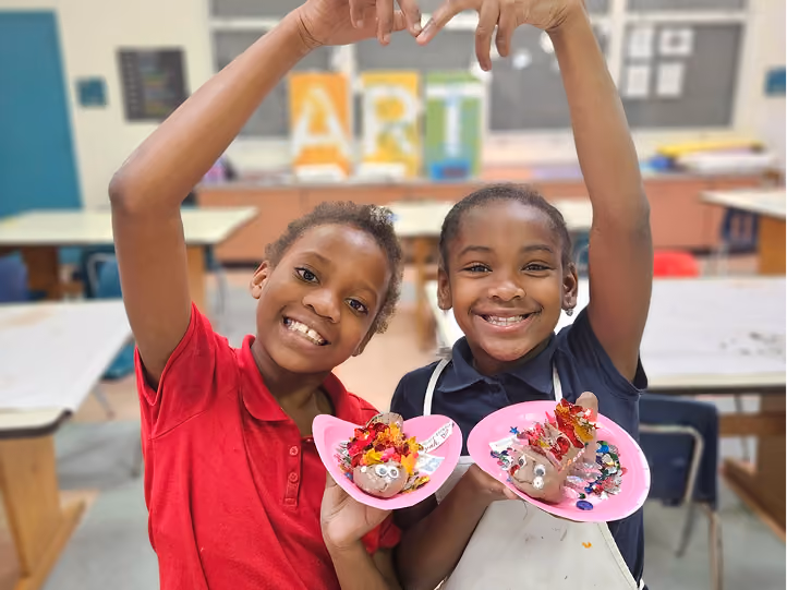 Two Kidcreate kids smiling with their finished group art project