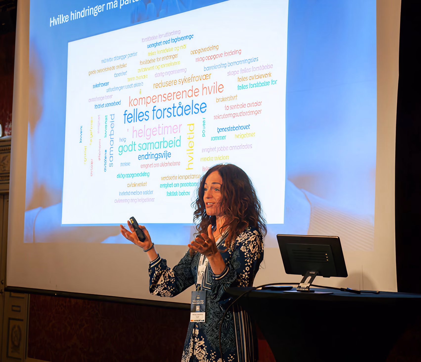 Kvinne holder presentasjon foran skjerm med ordsky om hindringer for deltakelse.