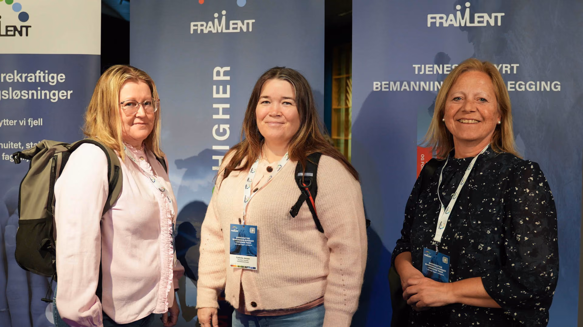 Tre kvinner med navneskilt står foran bannere med teksten Framlent på en konferanse.
