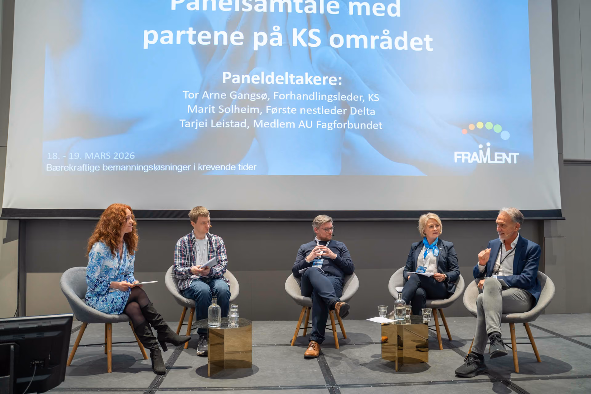Paneldiskusjon med fem deltakere på scene foran skjerm med tekst om KS-området og bærekraftige løsninger.