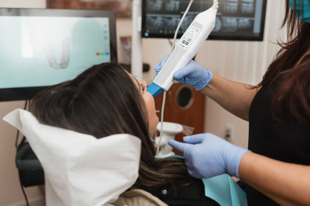 Dental professional using scanner device to take digital impressions of patient’s teeth in dental office.