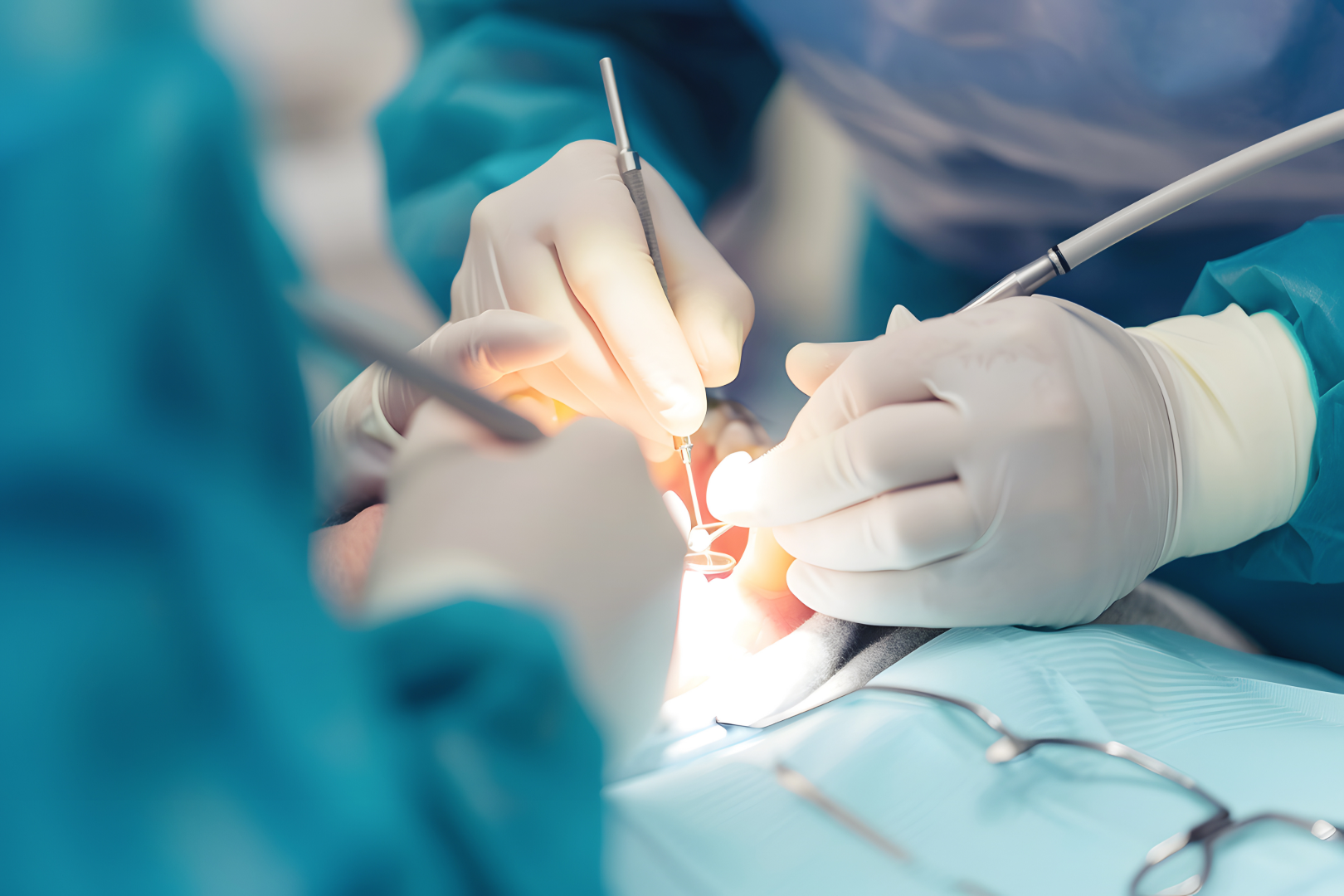 Close-up of dentists wearing gloves performing dental procedure with tools inside a patient's mouth.