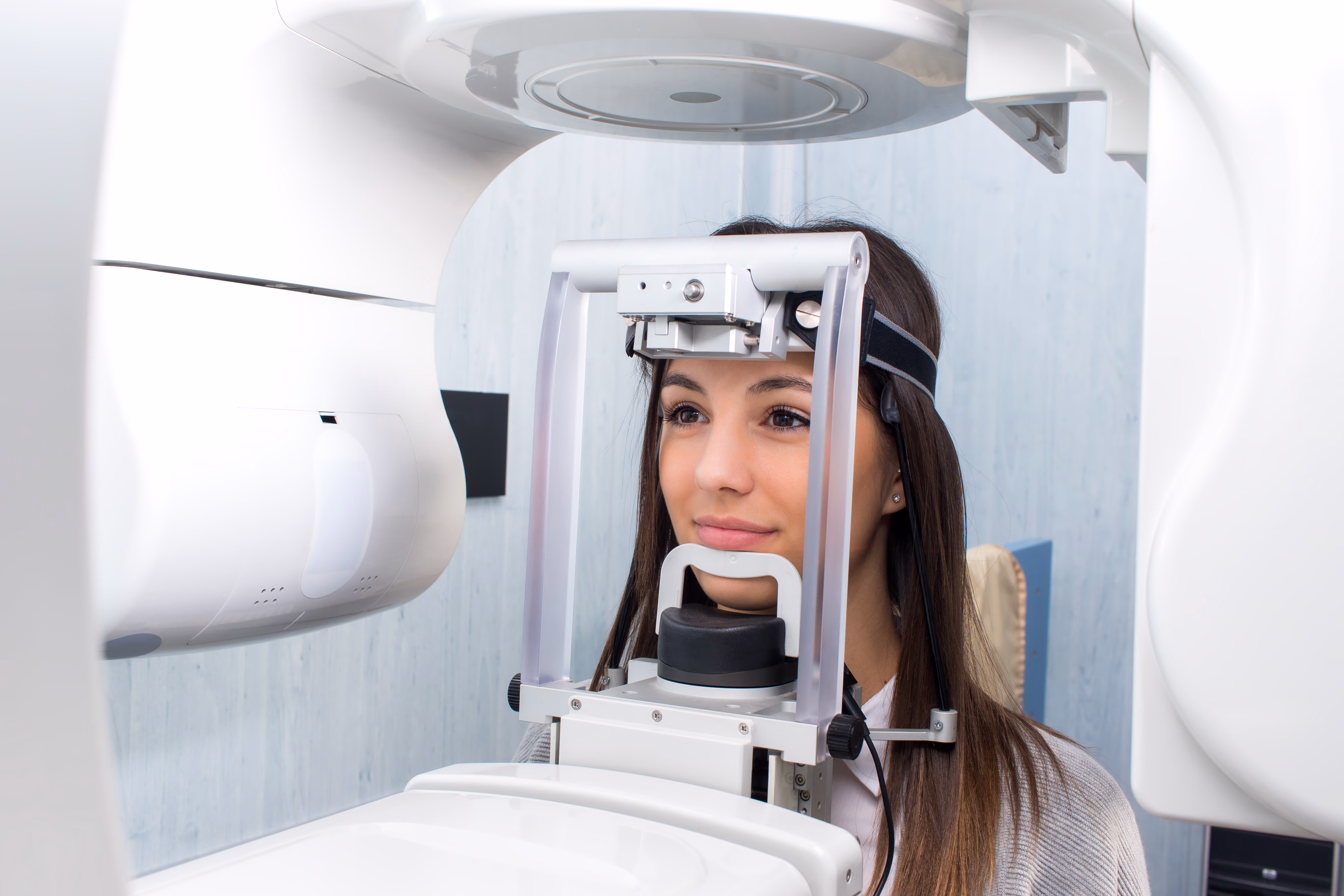 Woman undergoing a dental panoramic X-ray with her head positioned in the imaging machine.