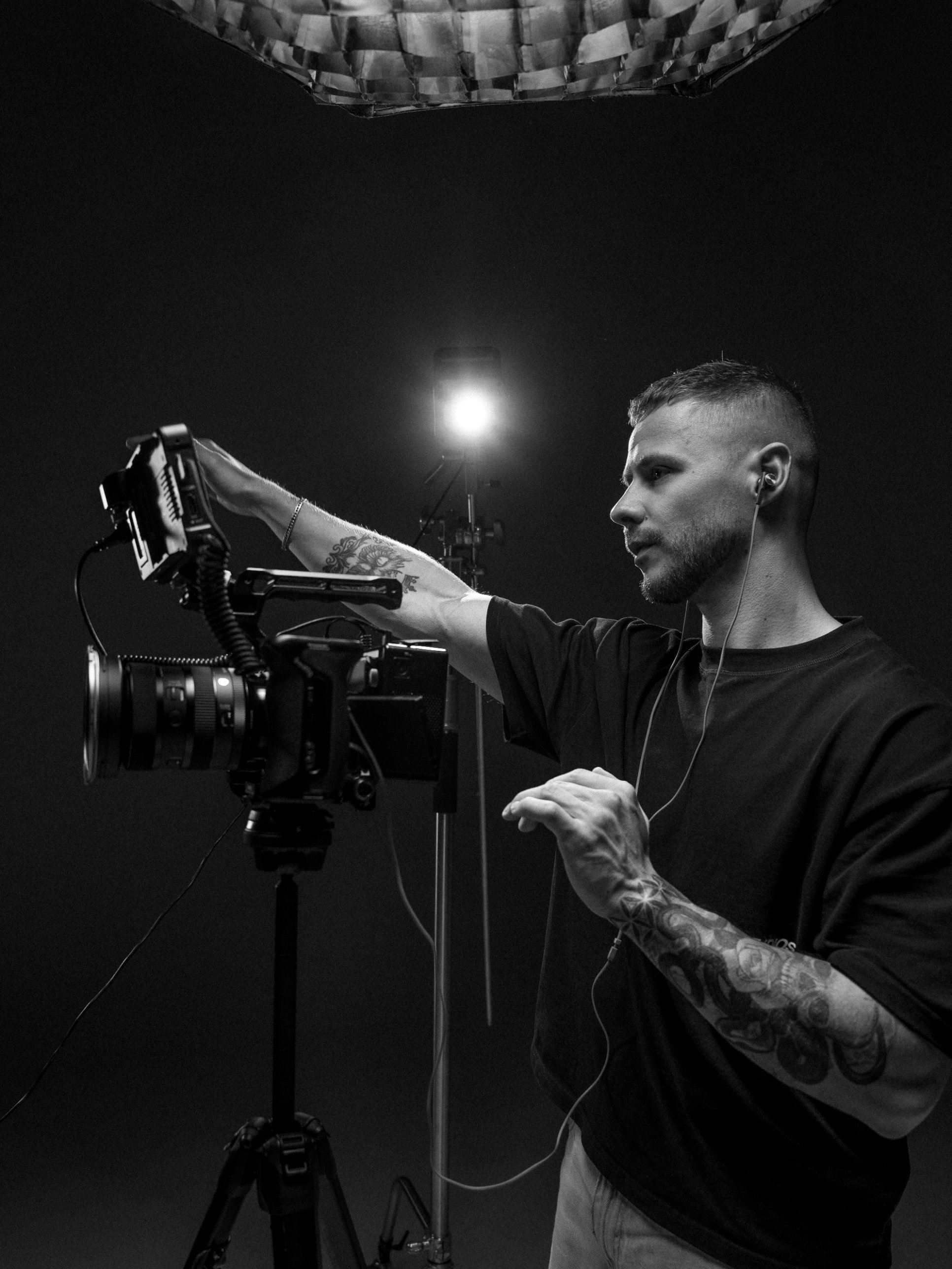 Christophe Schmitt in zwart-wit, stelt een camera af in de studio onder een studiolamp