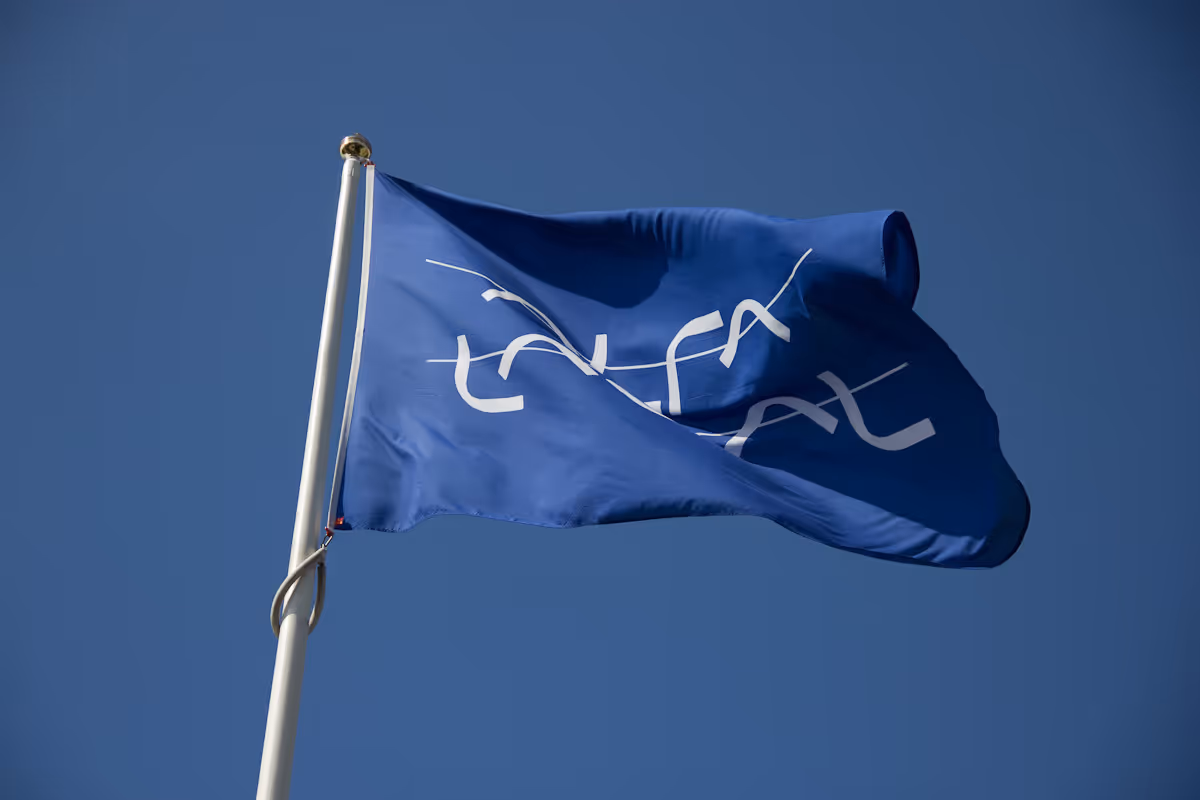 Blå flagg med hvit Alfa Laval-logo som vaier mot blå himmel.