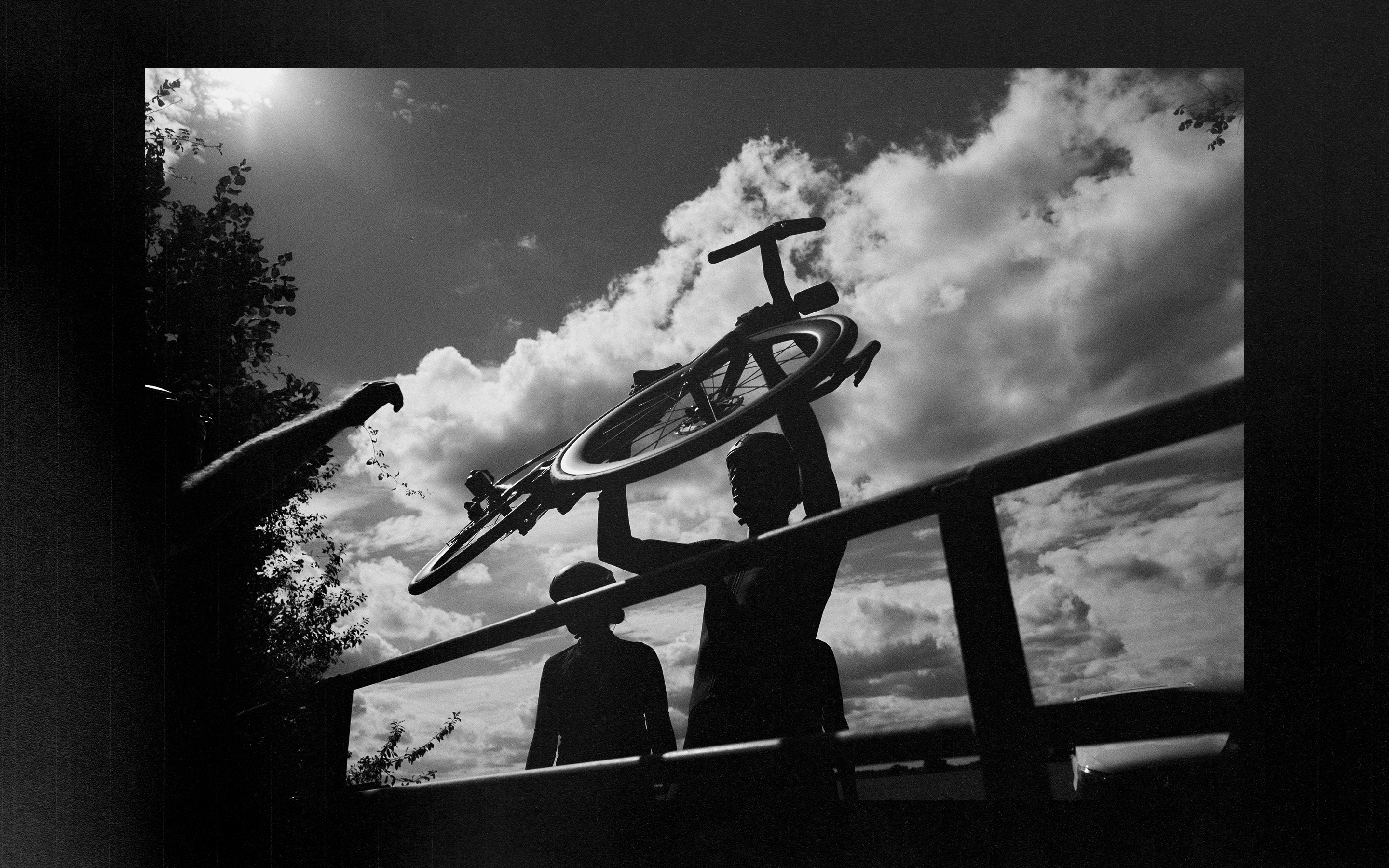 A rider lifts a bicycle overhead in a black-and-white contact-sheet-style layout.