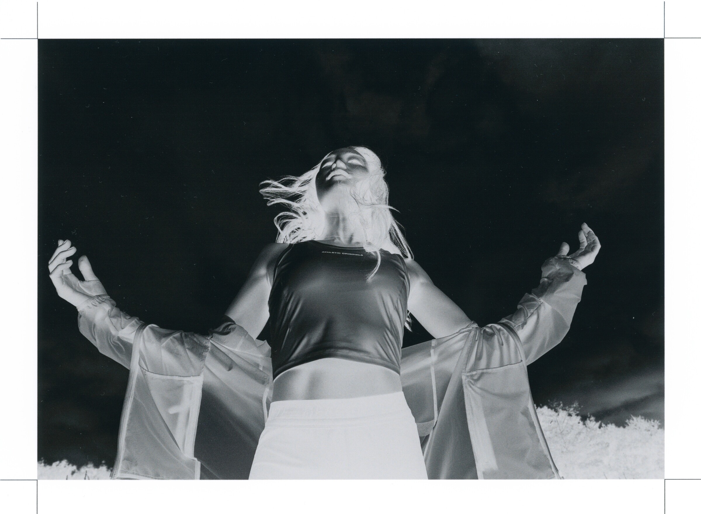 DESCENTE Athletic Originals: Negative-style monochrome image of a woman opening her jacket beneath the sky.