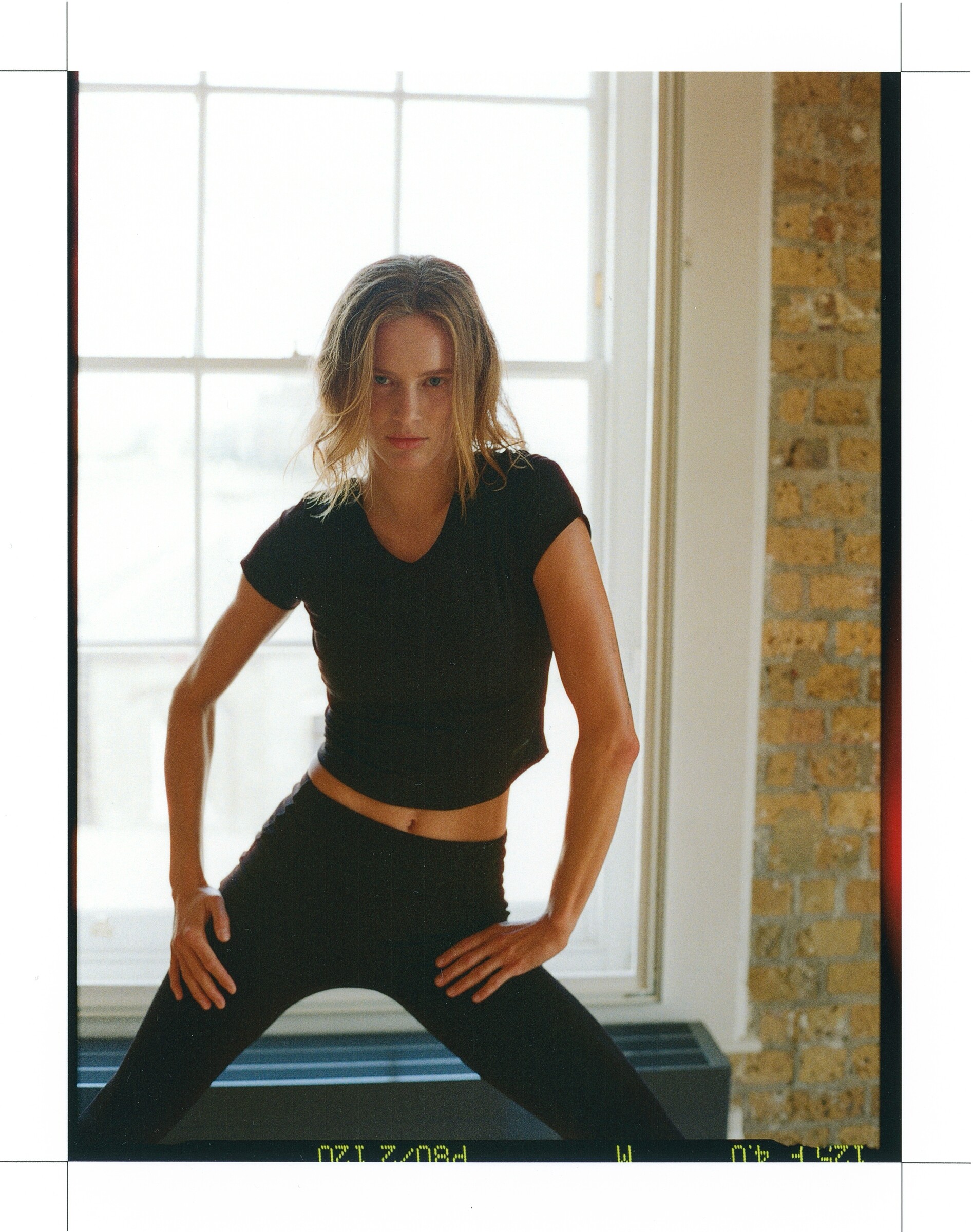 DESCENTE Athletic Originals: Dancer leaning forward with hands on her thighs in a sunlit studio.