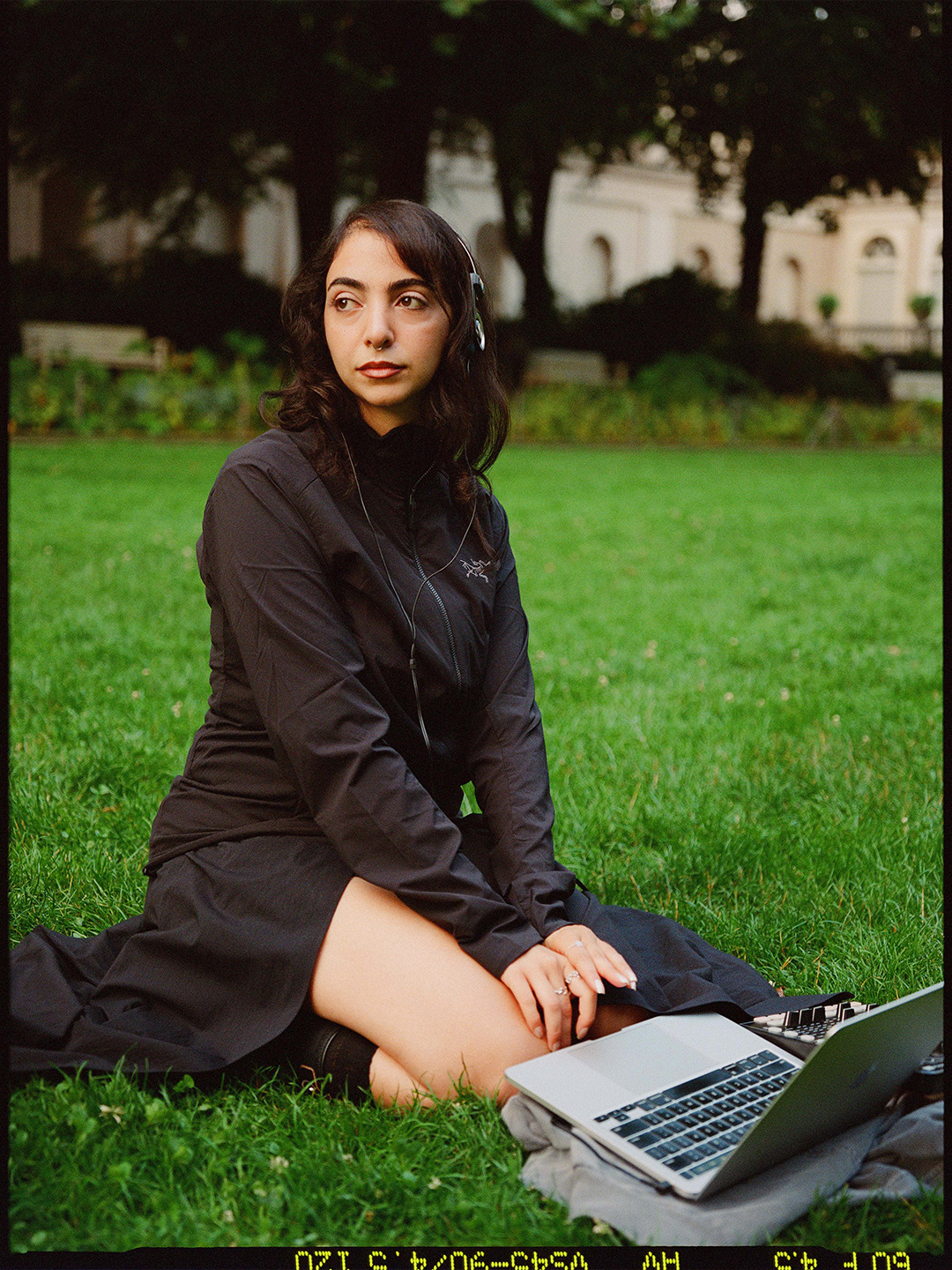 Arc'teryx Translating Flow State: Sound artist seated on a lawn with a laptop, photographed on film.