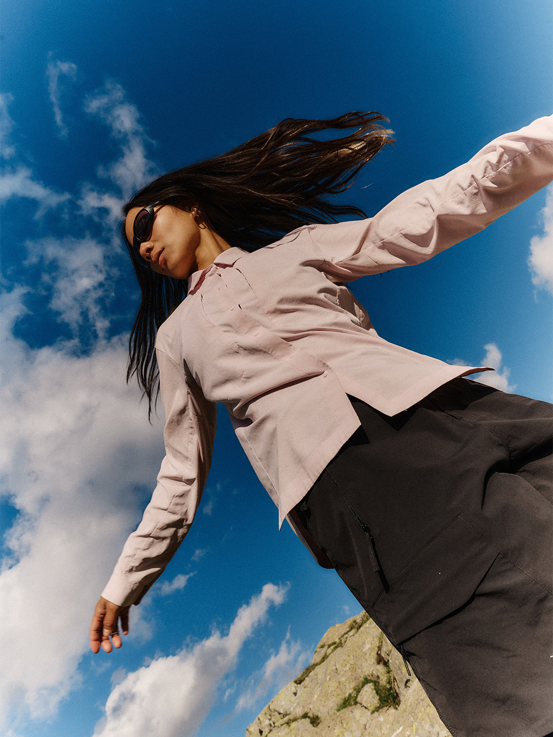 Arc'teryx Translating Flow State: Low-angle portrait of a hiker moving beneath a vivid blue sky.