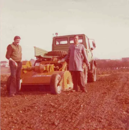 Historisches Foto: zwei Männer neben einer Maschine auf dem Feld, 1980