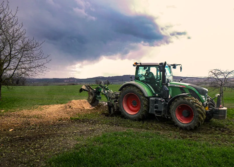 Traktor mit Stockfräse fräst einen Wurzelstock