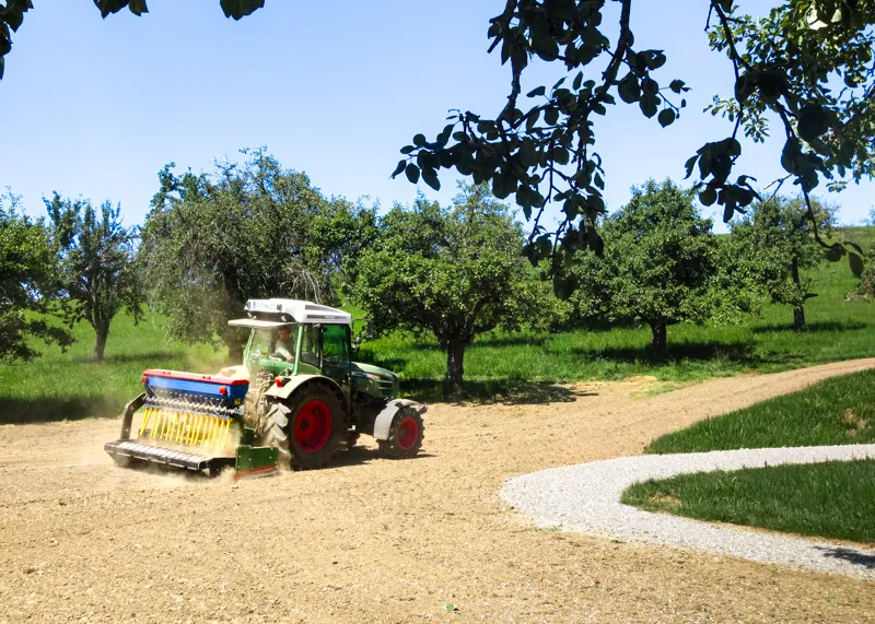 Traktor mit Sämaschine beim Begrünen einer Fläche