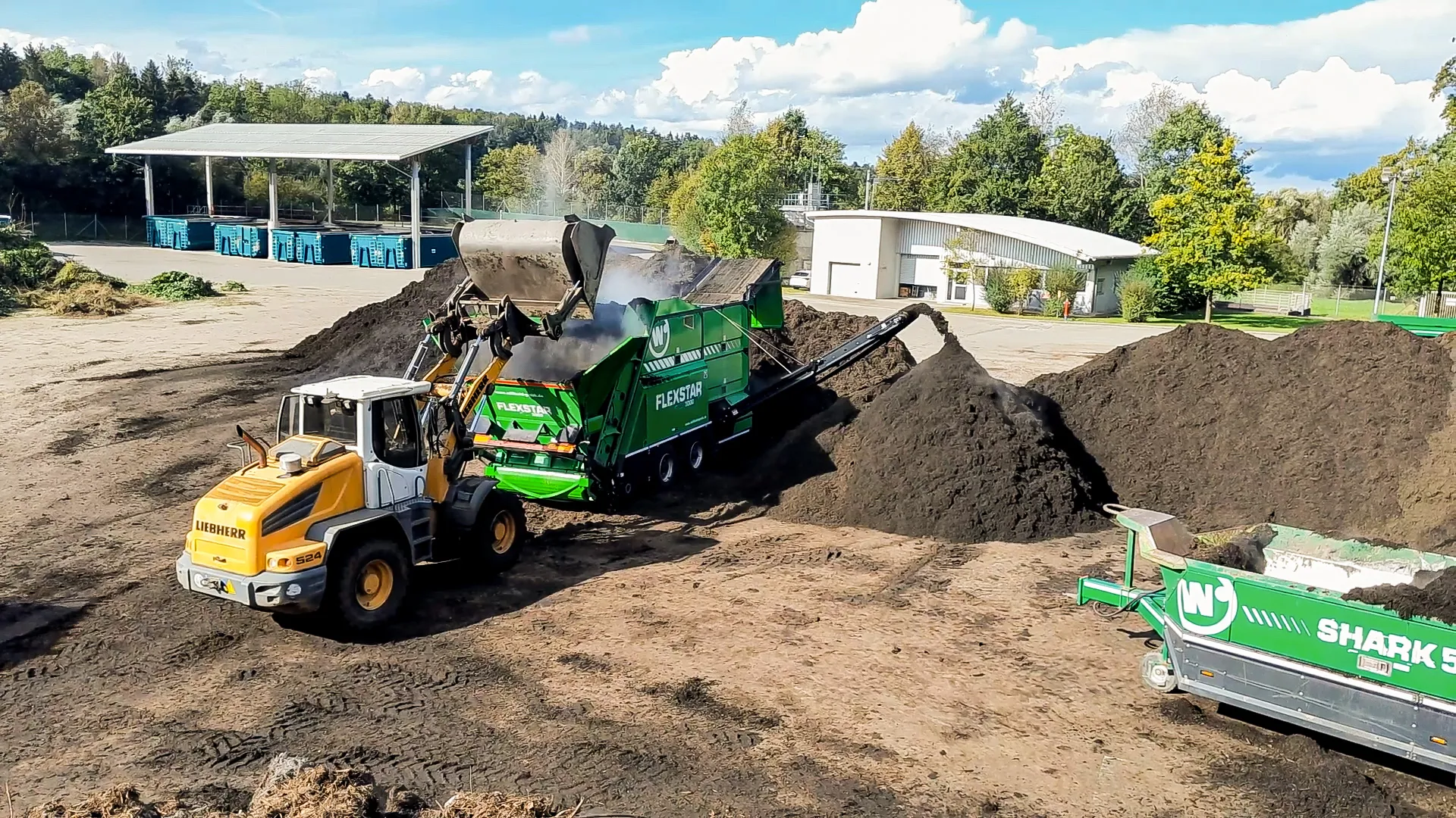 Radlader befüllt eine Siebanlage mit Kompost auf dem Kompostplatz