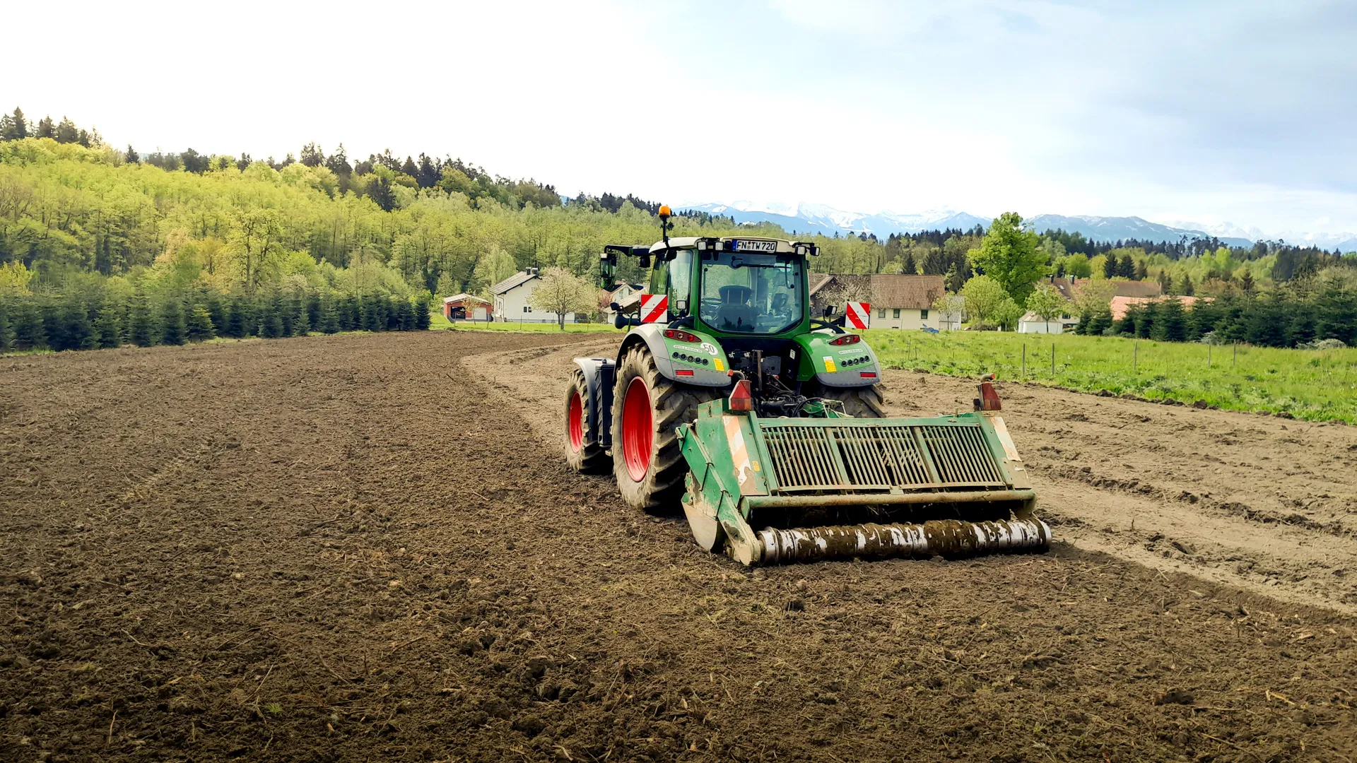 Traktor mit Spatenmaschine bei der Bodenbearbeitung auf einem Acker