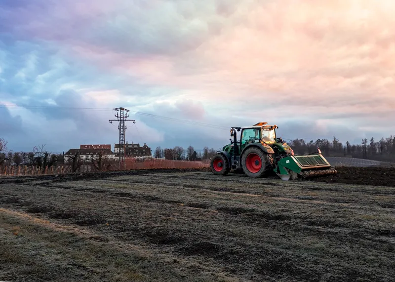 Traktor mit Bodenbearbeitungsgerät auf einer frisch bearbeiteten Fläche