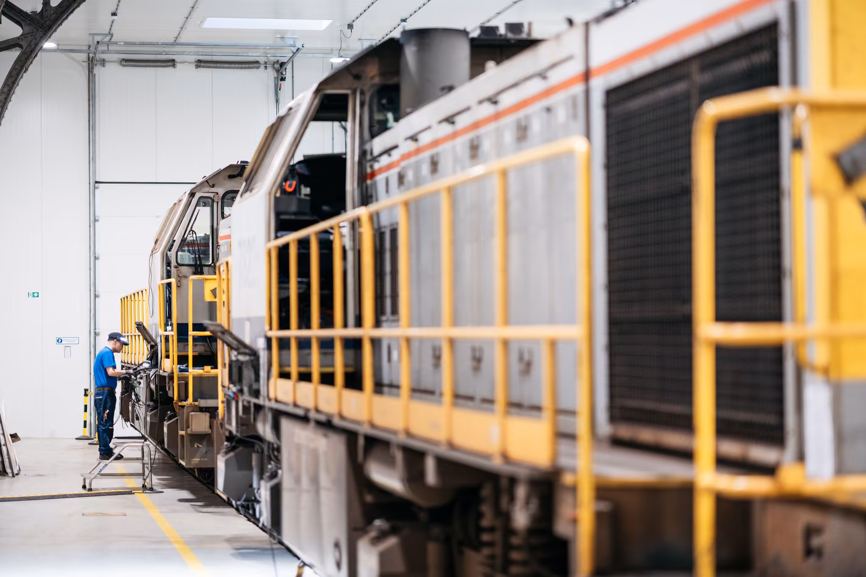 TSC technician working alongside a locomotive on a depot maintenance road.