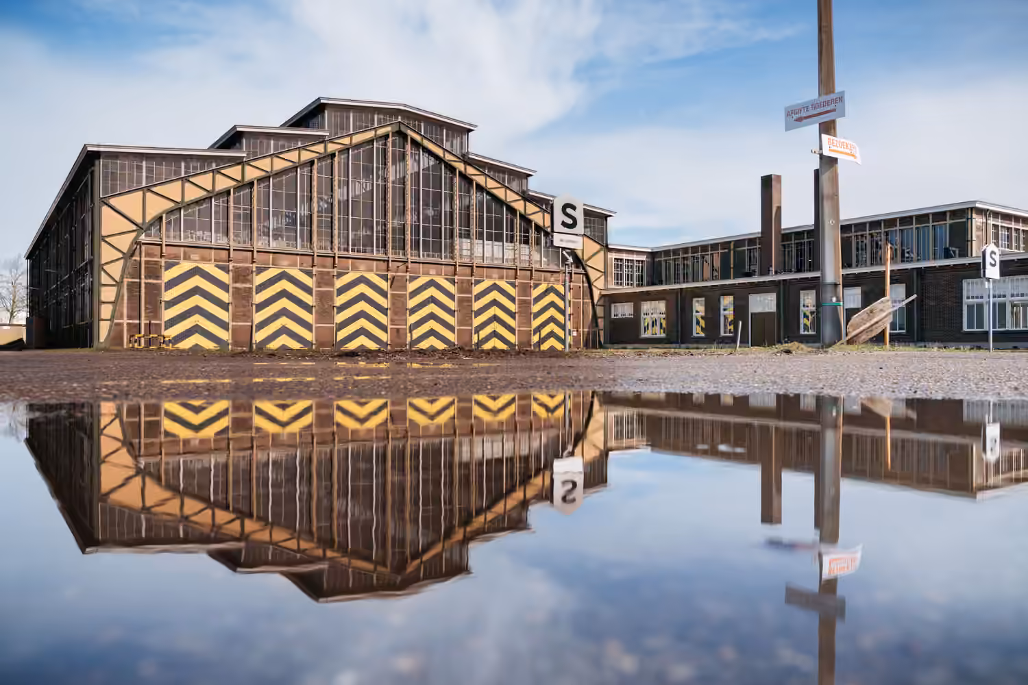 Historic depot building reflected in a rainwater pool outside.