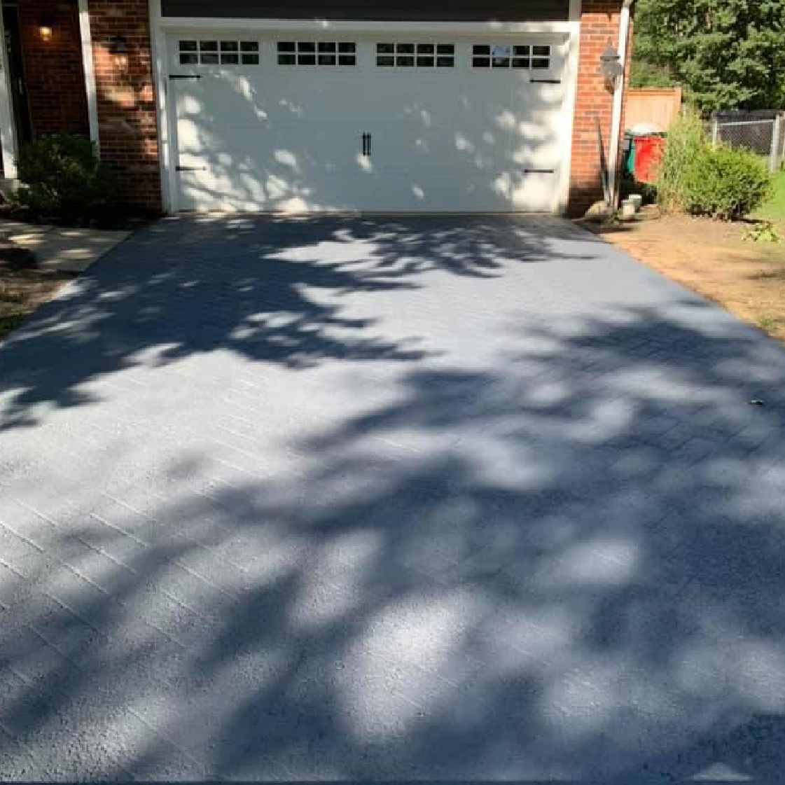 Newly sealcoated residential driveway in front of a white garage door