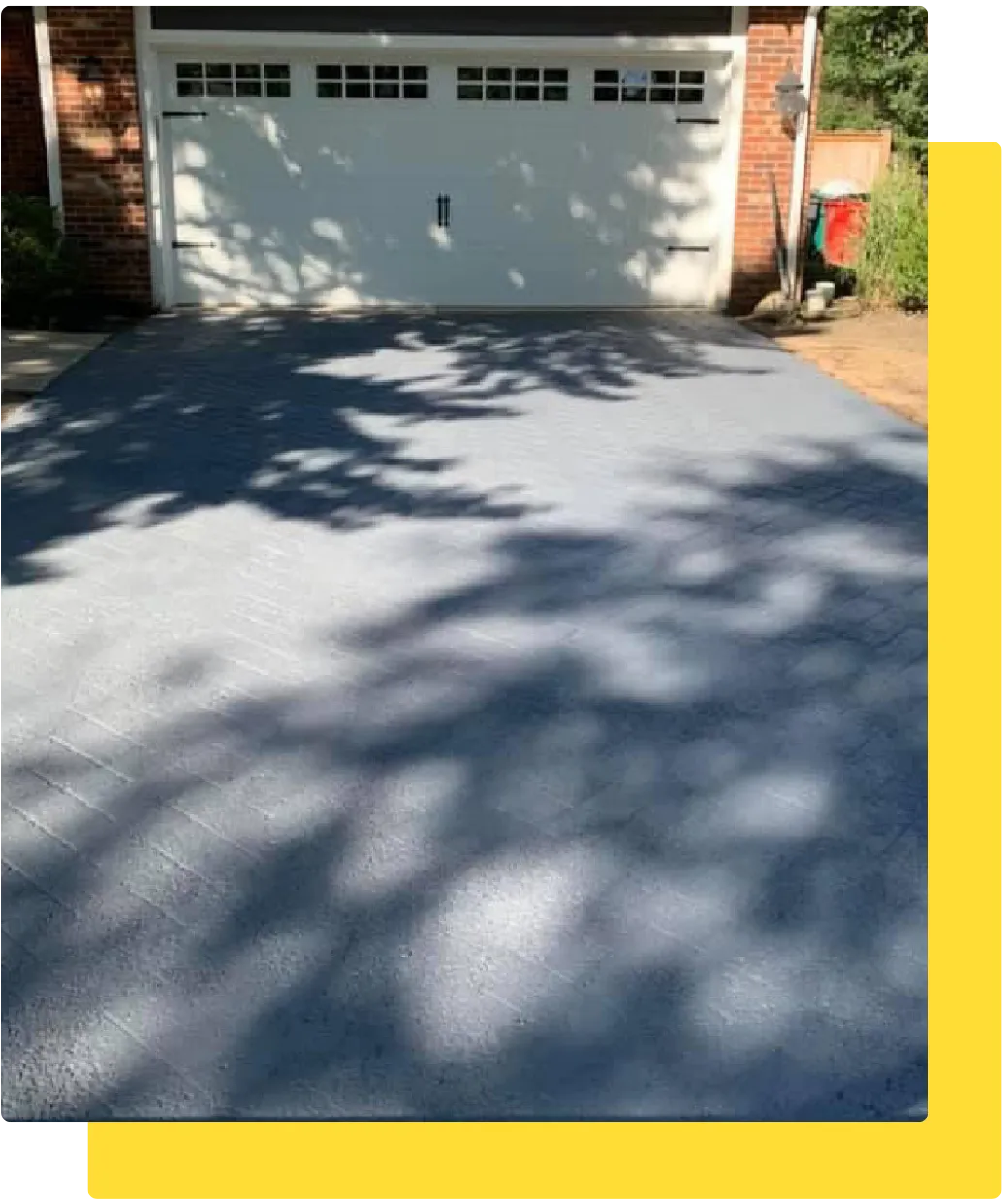 Newly sealcoated residential driveway in front of a white garage door