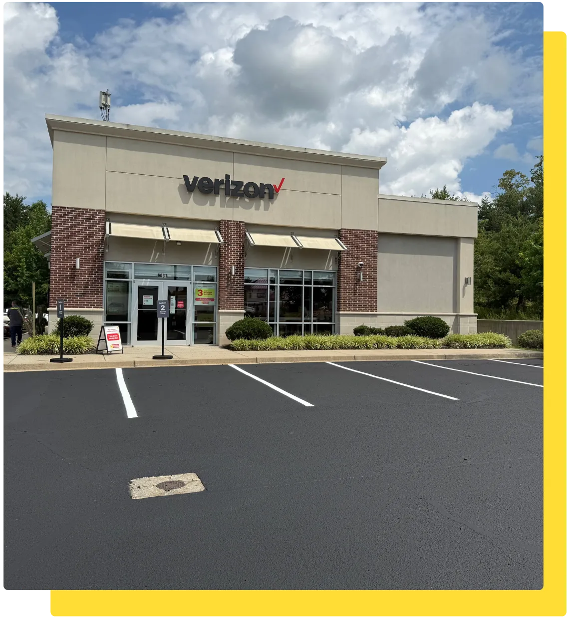 Sealcoated commercial parking lot with new white striping outside a Verizon retail store