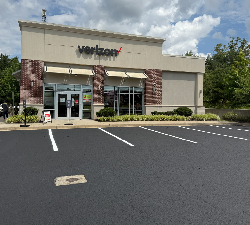 Sealcoated commercial parking lot with new white striping outside a Verizon retail store