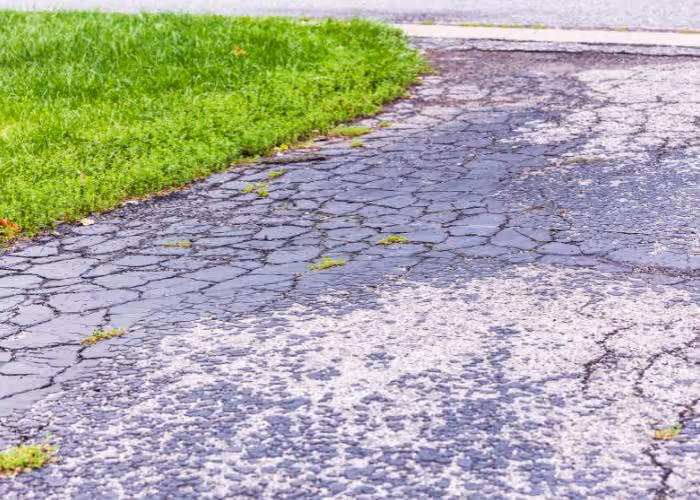 Crumbling, cracked edge of an asphalt driveway showing edge deterioration