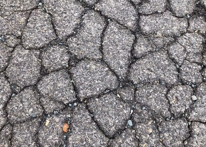 Alligator cracking spreading across worn asphalt pavement