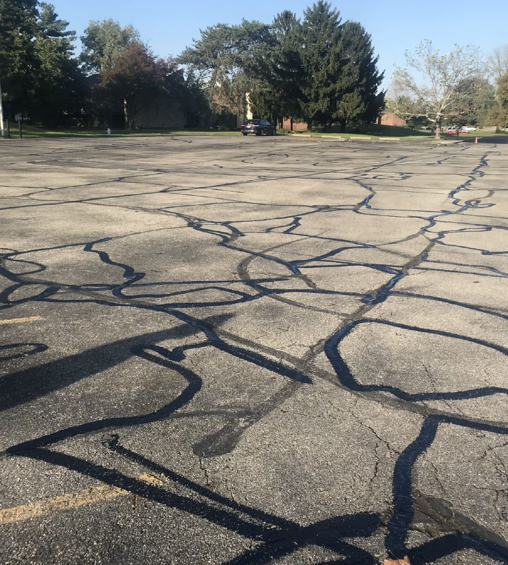 Commercial parking lot with hot rubberized crack sealant applied across cracked asphalt