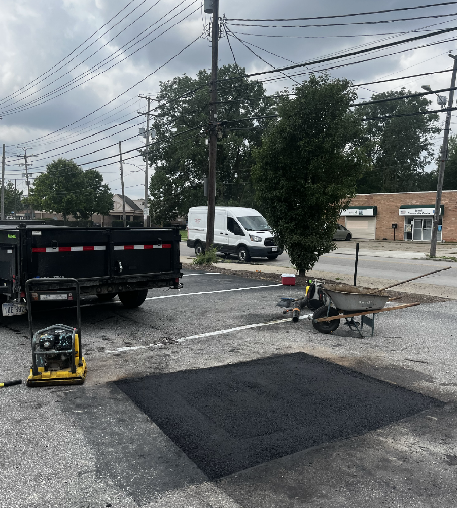 Freshly compacted asphalt patch with a plate compactor and A&D Asphalt dump truck