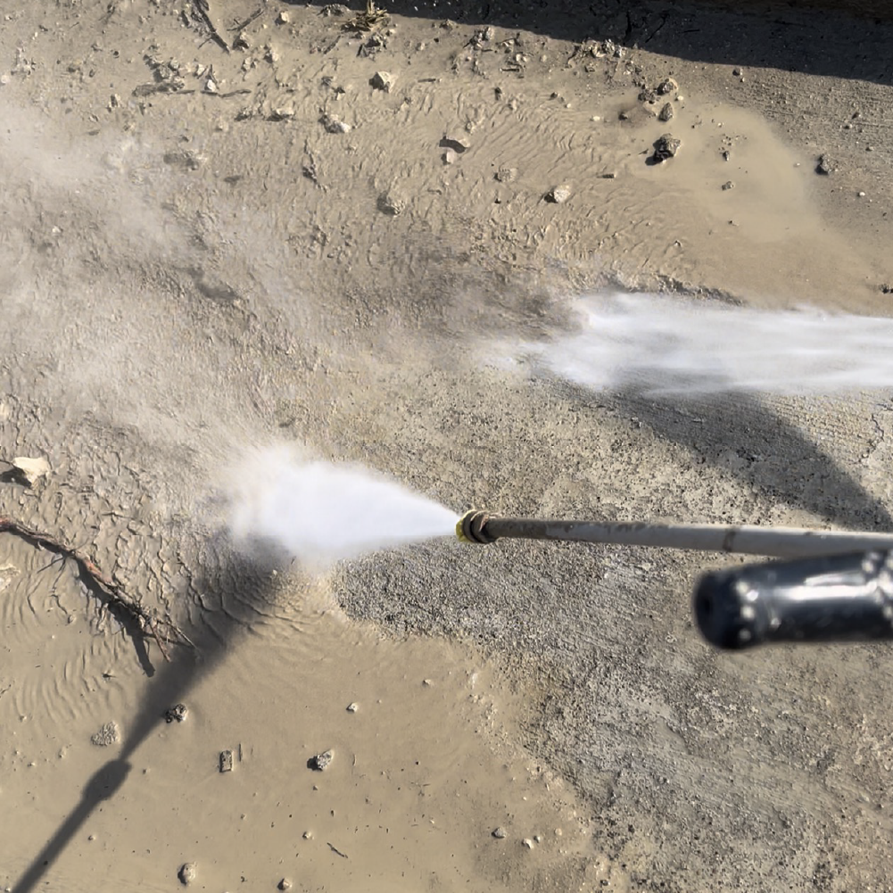 Pressure washing an asphalt parking lot surface to remove dirt and oil before sealcoating