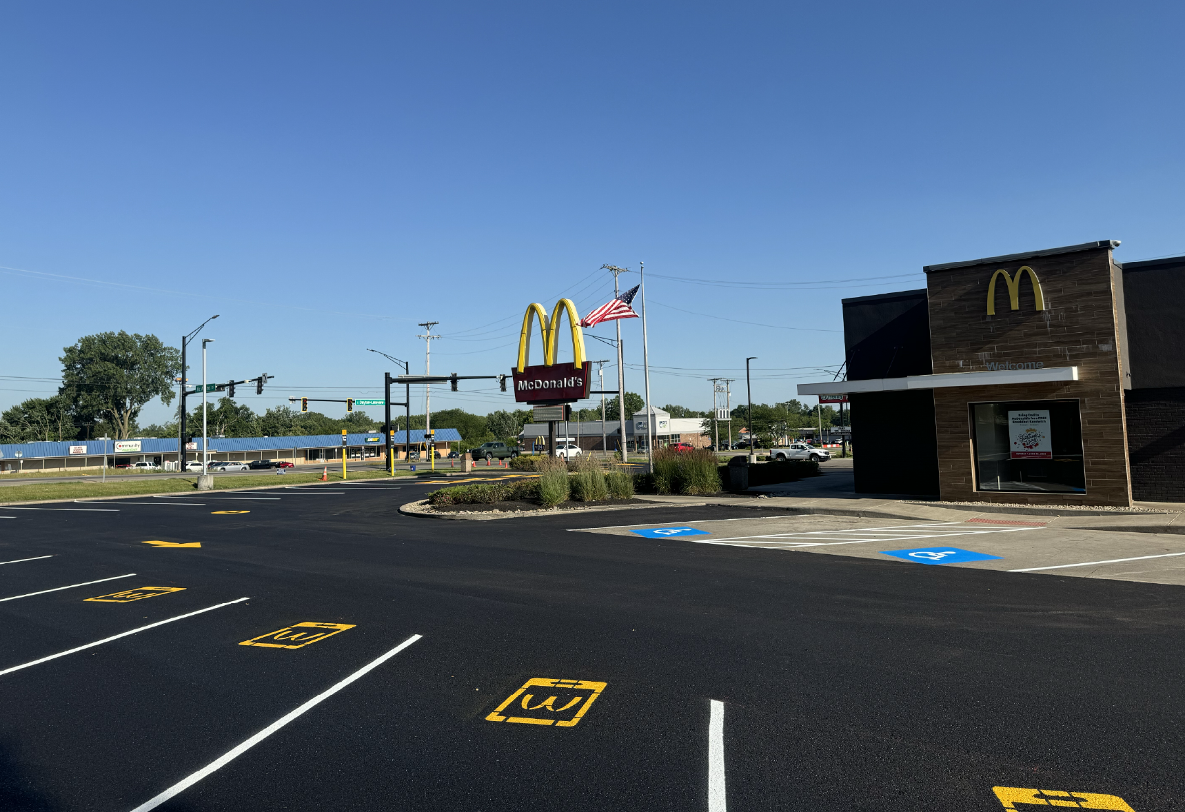Newly sealcoated and restriped McDonald's parking lot with fresh yellow parking lines by A&D Asphalt