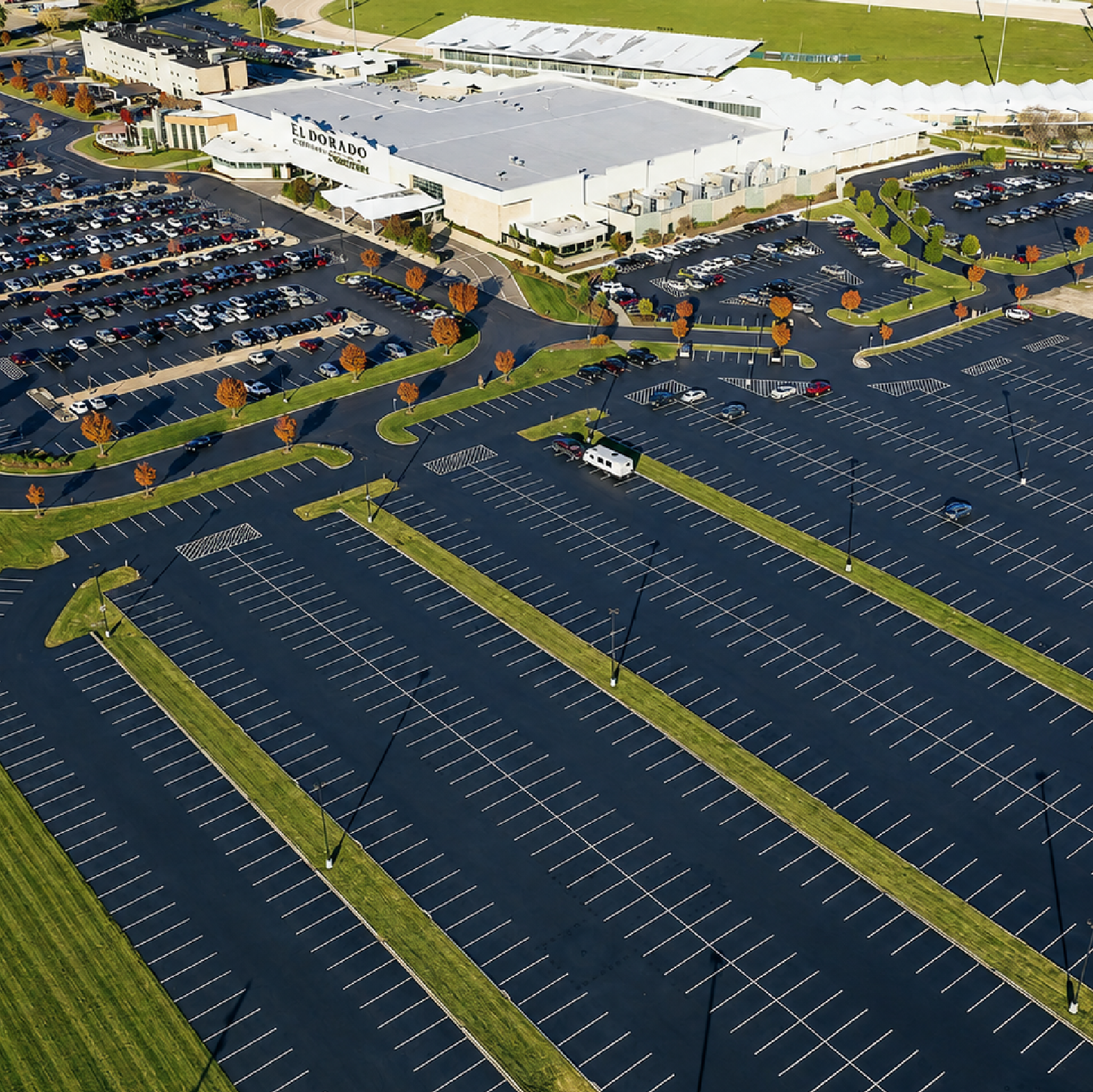 Aerial view of a large, freshly sealcoated and striped parking lot at a commercial facility