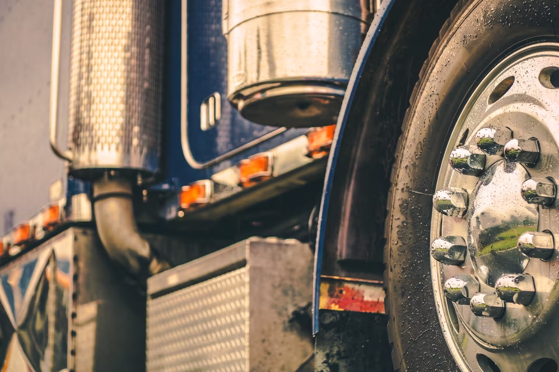 Close-up of a semi-truck's wheel, lug nuts, and exhaust stacks